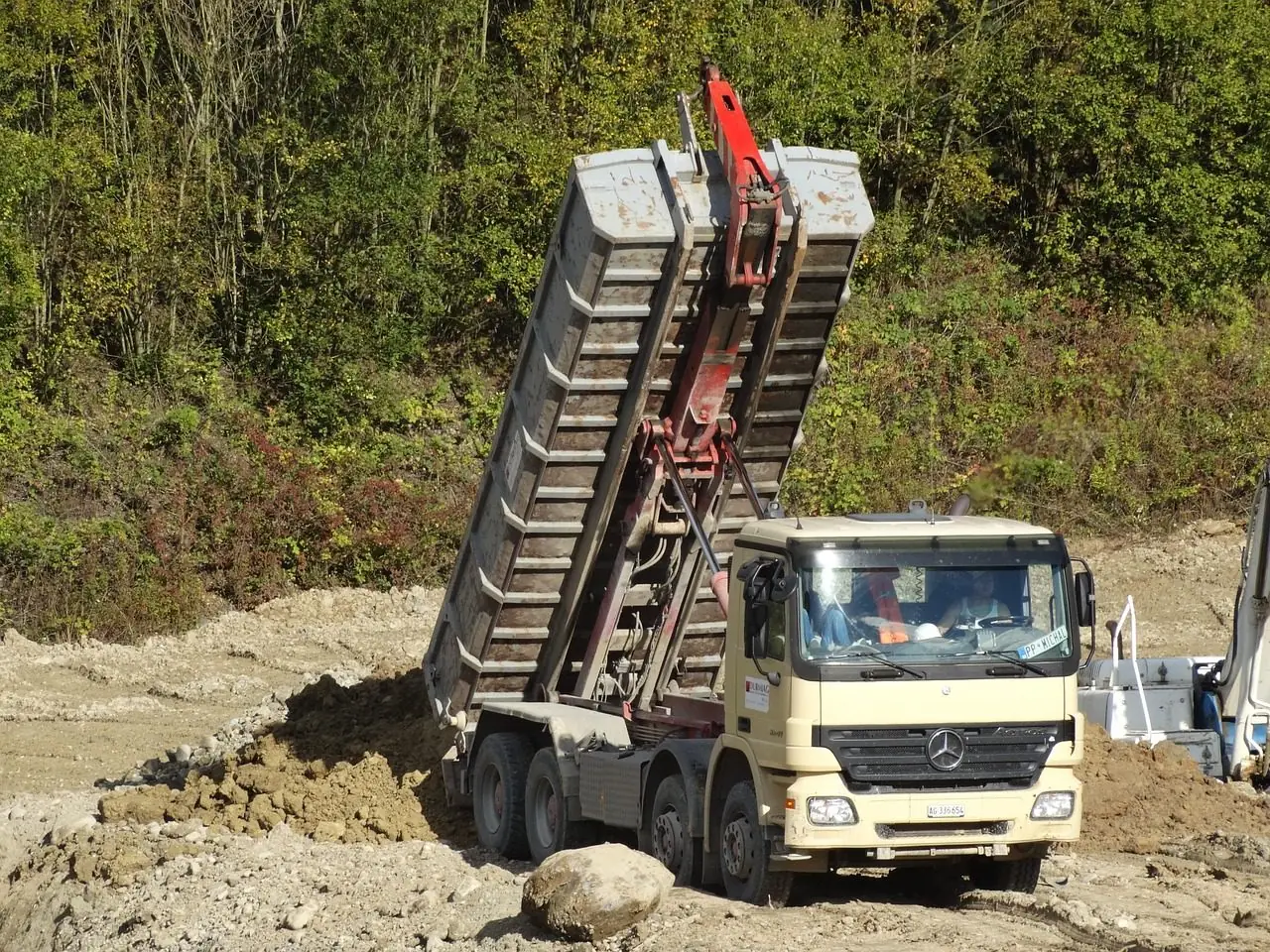 Dump truck tipping a load of soil at a work site