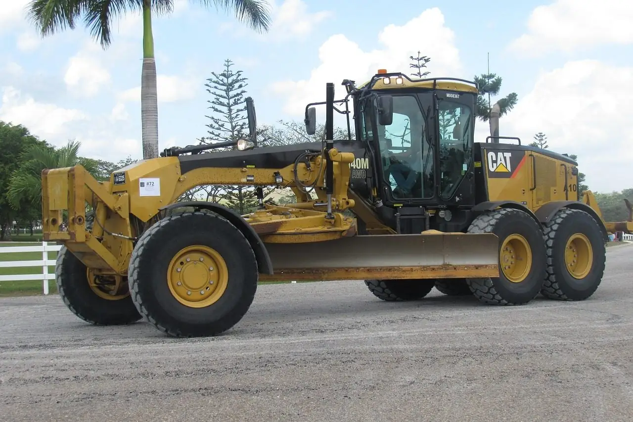 Yellow motor grader parked on a dirt road